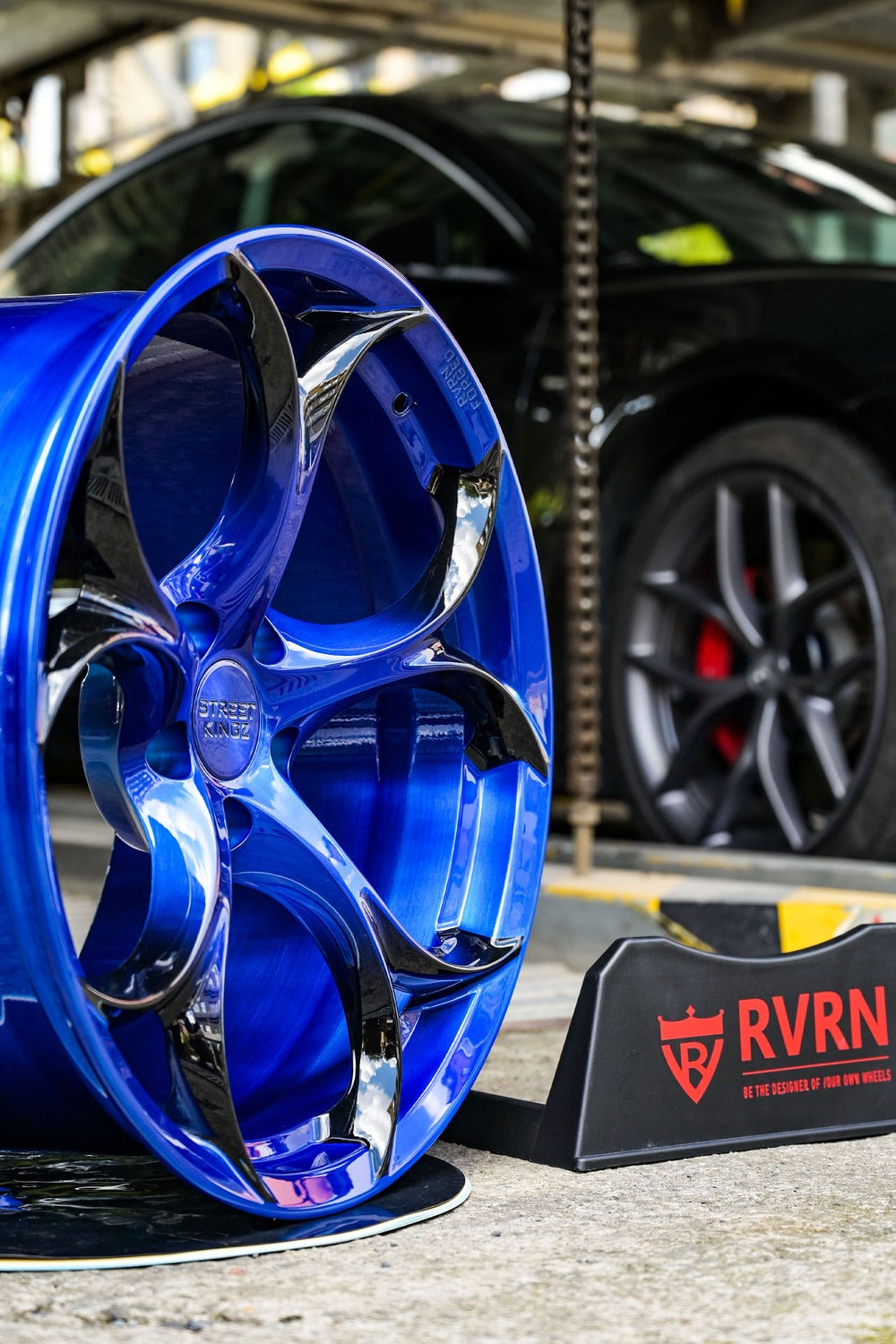 Bright blue forged rim on display with Corvette in the background, showcasing custom C7 wheels and high-performance design.
