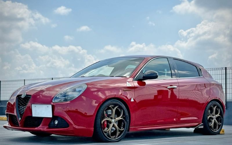 Alfa Romeo with bronze custom rims showcasing custom forged wheels in a bright outdoor setting.