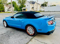 Blue Ford Mustang convertible with custom white and orange rims parked on the street.