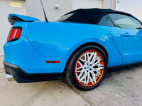 Ford Mustang featuring custom white and orange rims, showcasing a sleek blue convertible design.