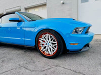 Ford Mustang with custom white and orange rims showcased in a sleek blue exterior.