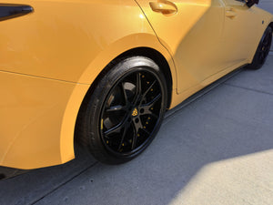 Close-up of the rear RVRN RV-DC24 gloss black split-spoke wheel with yellow screws on a yellow 2025 Lexus IS500