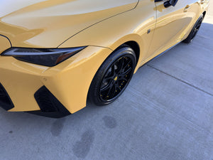 Close-up of the front RVRN RV-DC24 gloss black wheel with yellow screws on a yellow 2025 Lexus IS500, headlight in frame