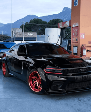 Front three-quarter view of a black 2023 Dodge Charger Hellcat Widebody on RVRN RV-DC39 rose gold wheels, mountains behind