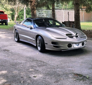 Front three-quarter view of a silver 2002 Pontiac Trans Am on RVRN RV-DC56 deep dish custom forged wheels parked near a red pickup