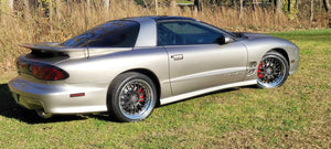 Rear three-quarter view of a silver 2002 Pontiac Trans Am on RVRN RV-DC56 deep dish custom forged wheels parked on grass