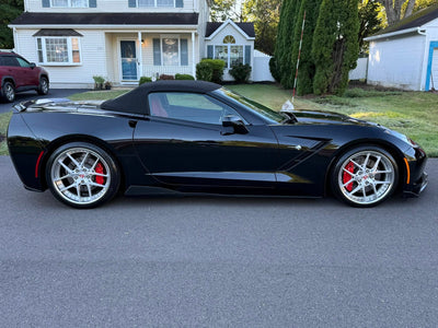 2016 Black C7 Corvette with chrome wheels parked outside, showcasing custom forged wheels and sleek design.