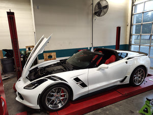 2017 C7 Corvette Grand Sport with aftermarket wheels, showcasing a sleek design and open hood in a garage.