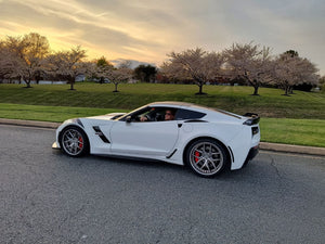 2017 C7 Corvette Grand Sport with aftermarket wheels parked under cherry blossoms at sunset.