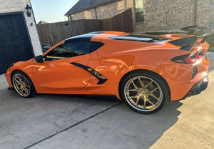 Rear three-quarter view of an orange 2024 Corvette C8 Stingray with rear wing on RVRN RV-DR08 deep dish gold chrome wheels, driveway