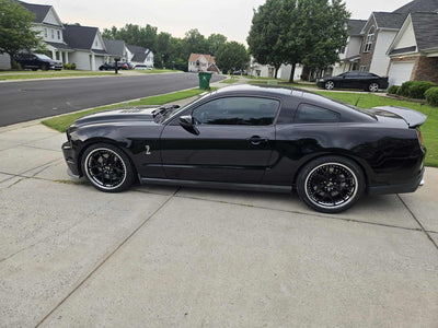 2011 Ford Shelby GT500 with custom forged black and chrome rims parked in a residential area.