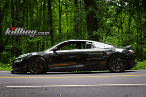 Side profile of a black 2008 Audi R8 on RVRN RV-DS016 custom forged wheels with gloss black gradient red spokes, forest background
