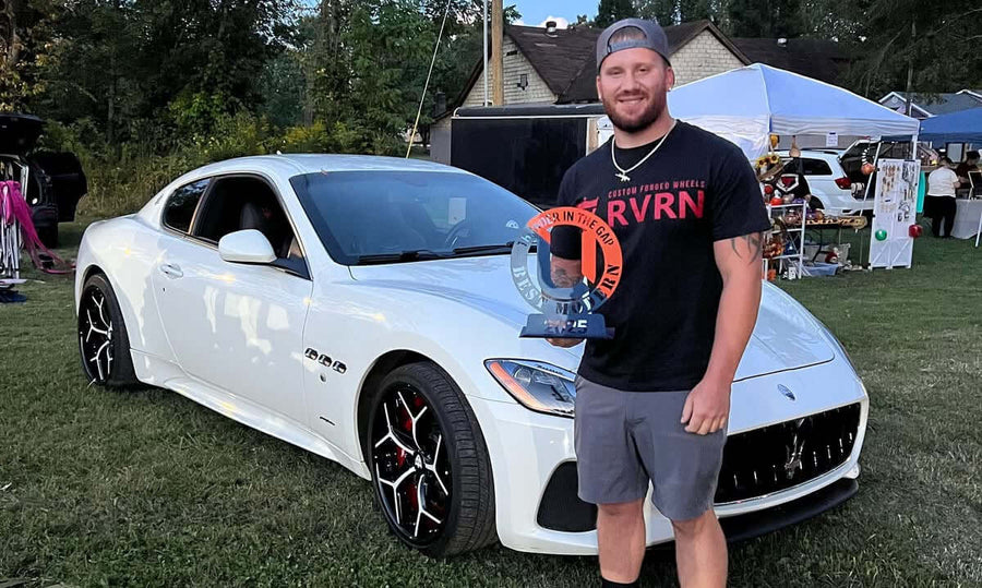 Customer showing off custom forged RVRN wheels at a car show, celebrating car design and craftsmanship.