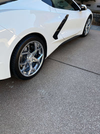 Close-up of a Corvette C8 showcasing polished aluminum aftermarket wheels on a driveway.