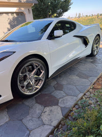 Corvette C8 featuring polished aluminum aftermarket wheels on a sunny driveway.