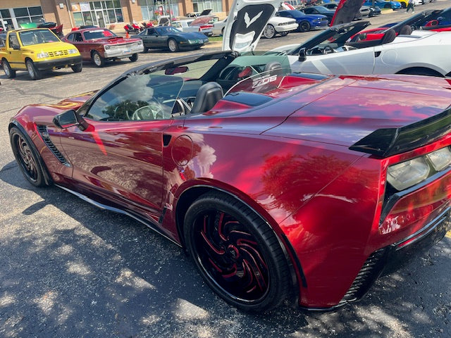 Red corvette sports car parked in a lot with other cars at community event