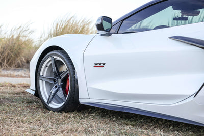 2023 Corvette C8 Z06 showcasing custom concave rims and carbon flash wheels, parked in a grassy area.
