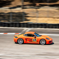Orange Porsche Cayman T with RVRN forged wheels, racing at Laguna Seca 2025, showcasing lightweight performance and track testing.