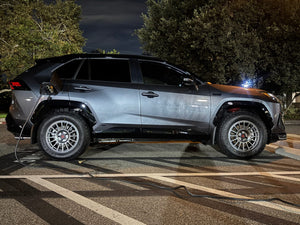 Side profile of a grey 2024 Toyota RAV4 Prime on RVRN RV-MT117 matte gunmetal custom forged wheels while charging at night