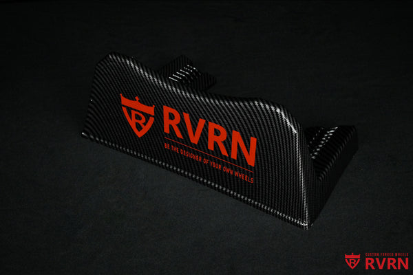 Angled view of the RVRN Custom Forged Wheels carbon-fiber-pattern display plaque with red RVRN branding.