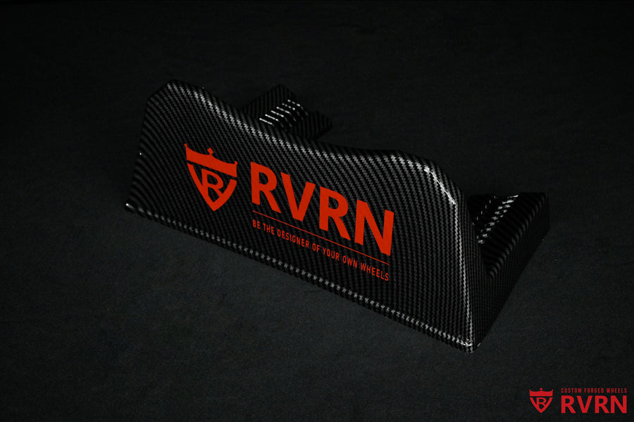 Angled view of the RVRN Custom Forged Wheels carbon-fiber-pattern display plaque with red RVRN branding.