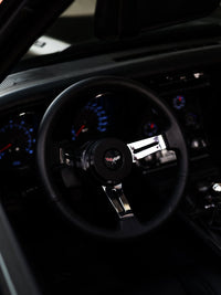 Interior of a 1973 C3 Corvette showing chrome steering wheel and blue dashboard gauges, featuring custom wheels.