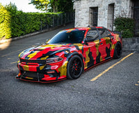 Custom Dodge Charger with 20-inch black deep dish rims, featuring a striking camouflage wrap design.