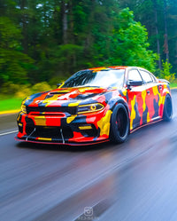 Dodge Charger with custom camouflage wrap and 20-inch black deep dish rim driving through forested road.