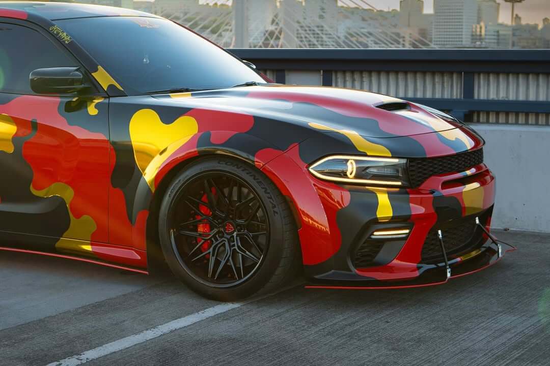 Dodge Charger with 20-inch black deep dish rim, featuring a vibrant camouflage wrap and custom forged wheels.