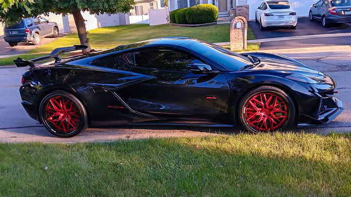 Side profile of a black 2024 Corvette C8 Z06 with rear wing on RVRN RV-T081 deep dish forged wheels with crystal burgundy spokes