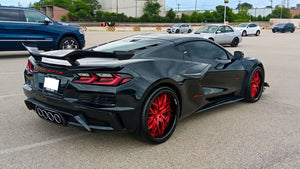 Rear three-quarter view of a black 2024 Corvette C8 Z06 on RVRN RV-T081 forged wheels with crystal burgundy spokes in a parking lot