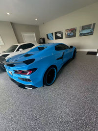 2025 Corvette Z06 in Rapid Blue with RVRN forged wheels and deep concave design, showcased in a stylish garage.