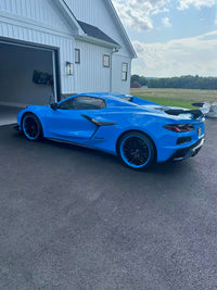2025 Rapid Blue Corvette Z06 showcasing custom RVRN RV-T081 forged wheels with deep concave design in a stylish garage setting.